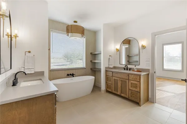 a spacious bathroom with a double vanity sink mirror and bathtub