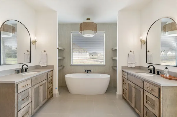 a bathroom with a double vanity sink a mirror and bathtub