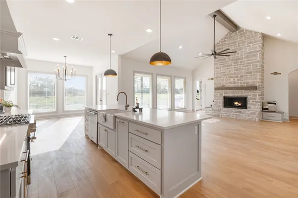 a large kitchen with stainless steel appliances kitchen island granite countertop a stove a sink a refrigerator and a fireplace