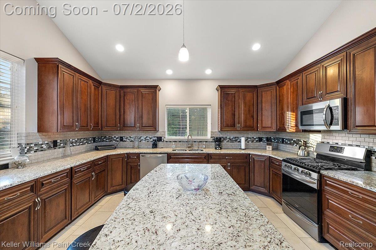 54230 Card Road Macomb, MI 48042 - Photo 40 of 73 Spacious kitchen featuring extensive wood cabinetry, light-toned countertops, and a central island