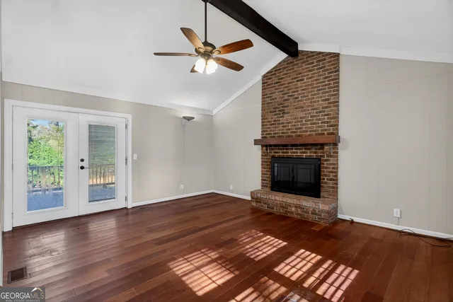 a view of an empty room with wooden floor fireplace and a window