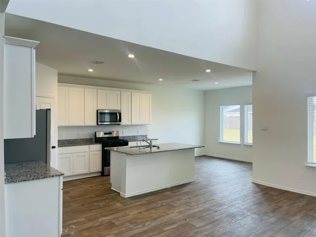 a kitchen with stainless steel appliances a stove top oven a sink a refrigerator and cabinets