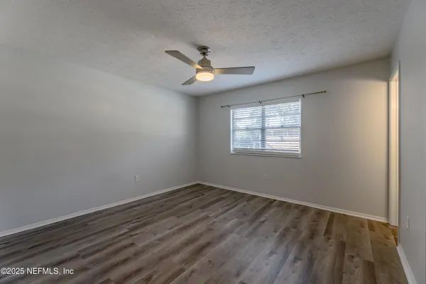 an empty room with a window and ceiling fan