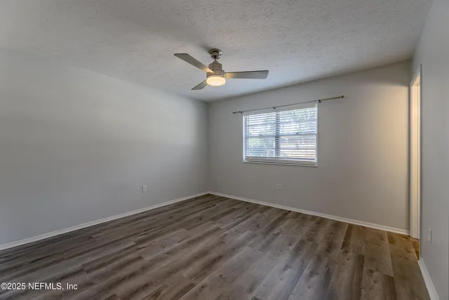 an empty room with a window and ceiling fan