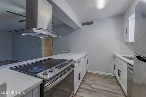 a view of kitchen and empty room with wooden floor