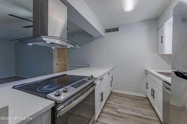 a view of kitchen and empty room with wooden floor