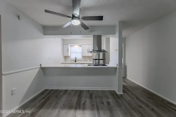 a view of kitchen and empty room with wooden floor