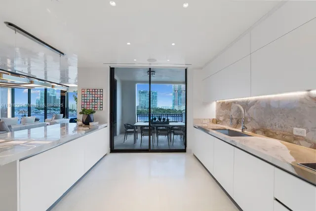 a large white kitchen with a large window and stainless steel appliances