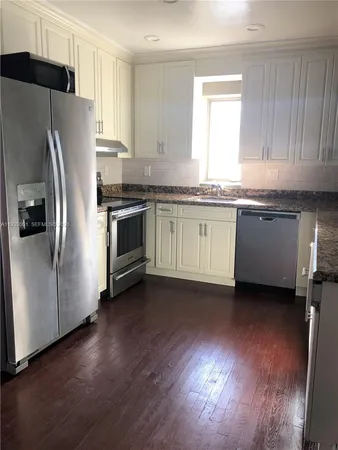 a kitchen with granite countertop stainless steel appliances a sink a refrigerator a window and cabinets