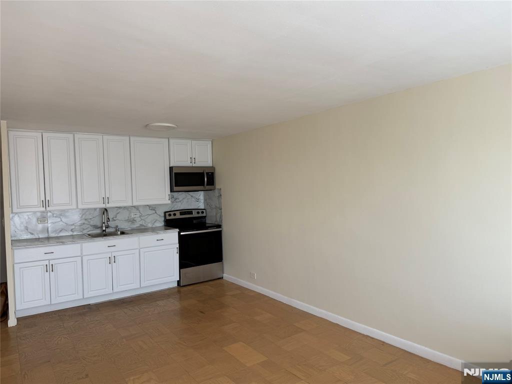 265 Main Street, Unit 702 Ridgefield Park, NJ 07660 - Photo 11 of 20 a kitchen with granite countertop white cabinets and stainless steel appliances