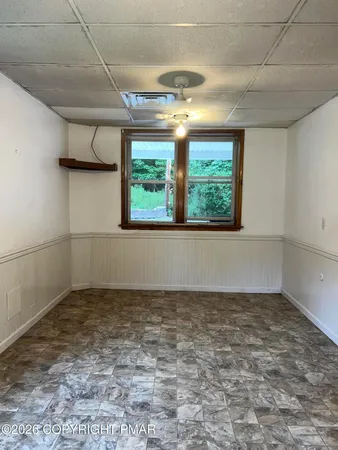 an empty room with a chandelier fan and windows