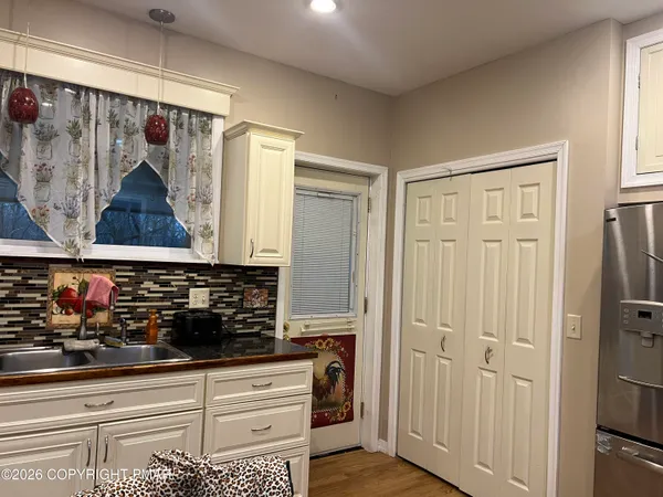 a view of a hallway with wooden floor and a bathroom