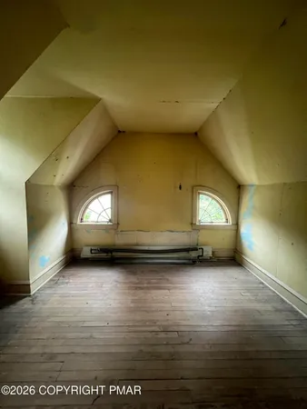an empty room with wooden floor chandelier and windows