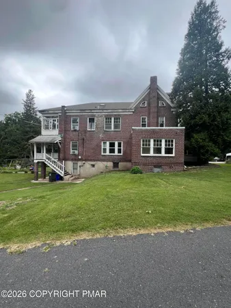 a front view of a house with a garden and trees
