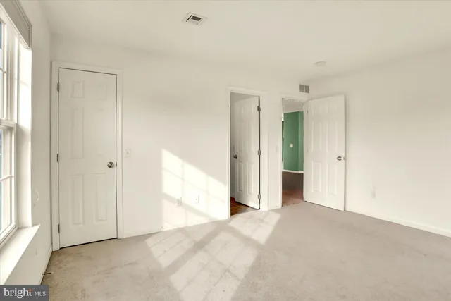 an empty room with window and bathroom