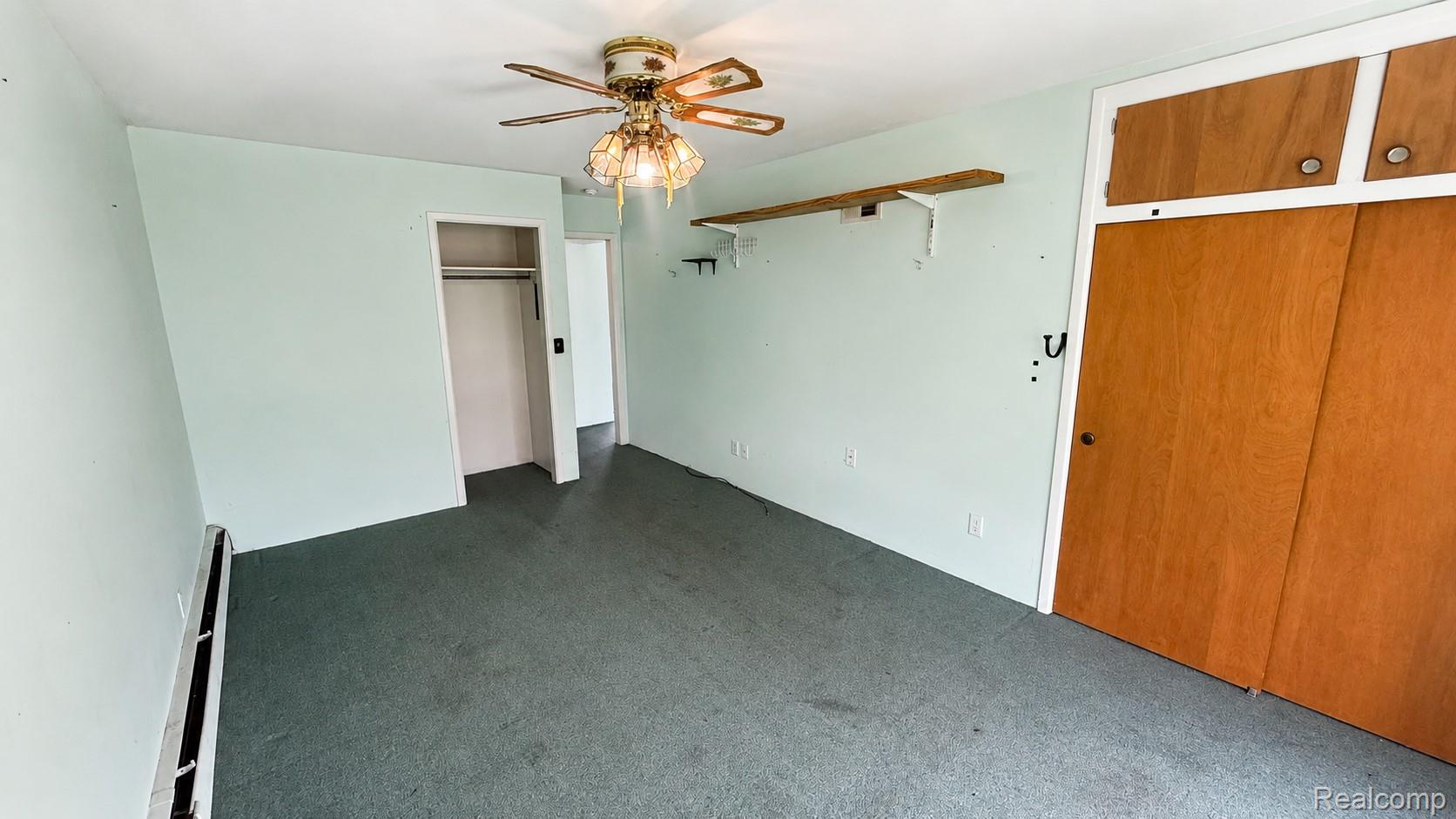 26945 Milford Road, Unit 34 New Hudson, MI 48165 - Photo 13 of 16 Room featuring light green walls, grey carpeting, and a ceiling fan with an ornate light fixture