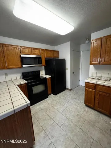 a kitchen with stainless steel appliances kitchen island granite countertop a refrigerator and a stove top oven