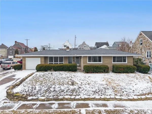 a front view of a house with a yard covered with snow