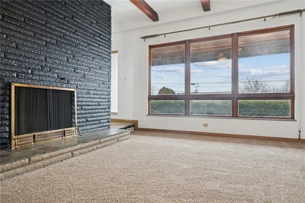 a view of an empty room with a fireplace and a window
