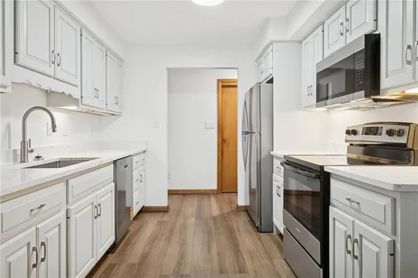 a kitchen with stainless steel appliances a stove microwave and a sink