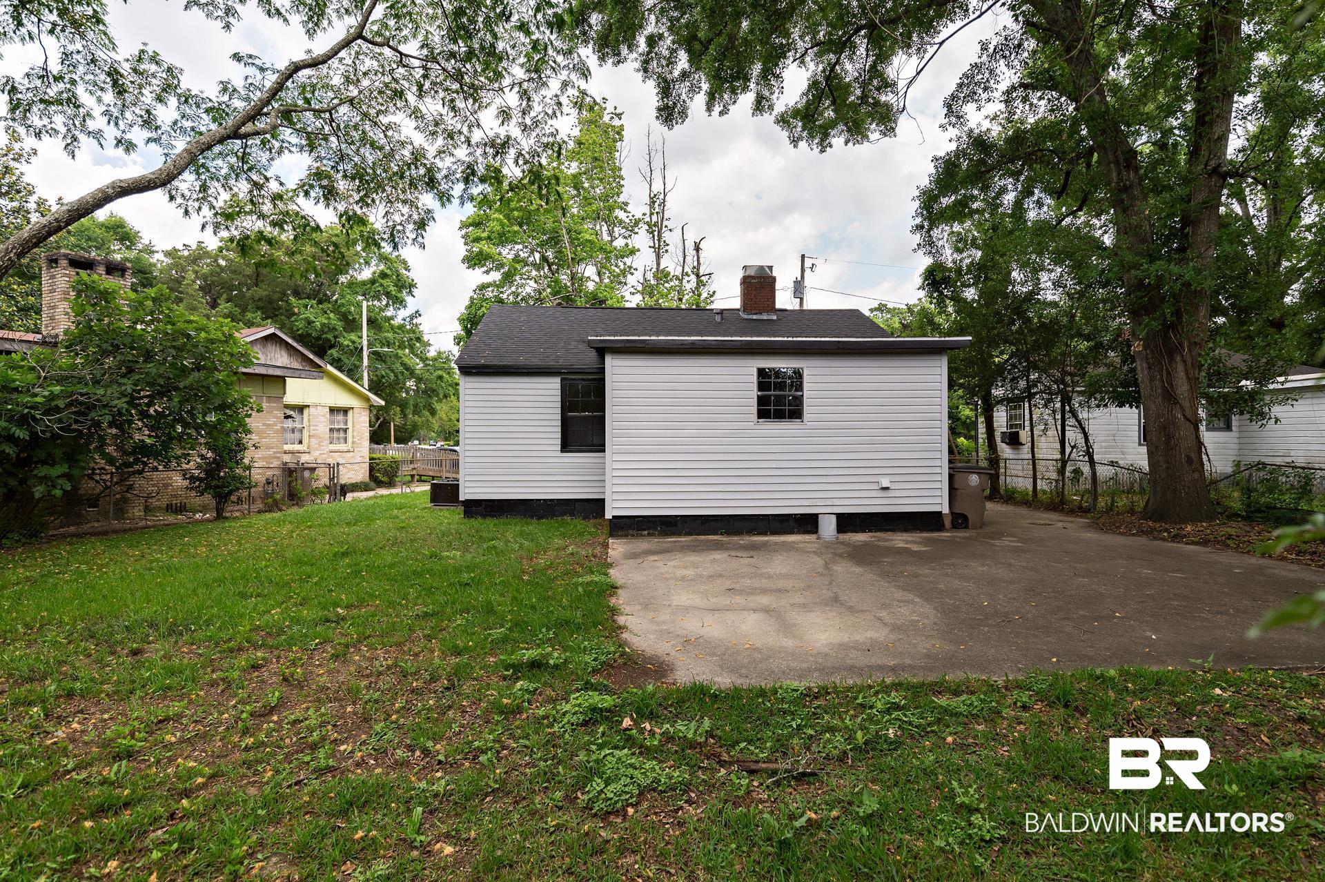 1869 Mott Drive West Mobile, AL 36617 - Photo 29 of 34 Back of house featuring fence, a lawn, a chimney, and a patio area