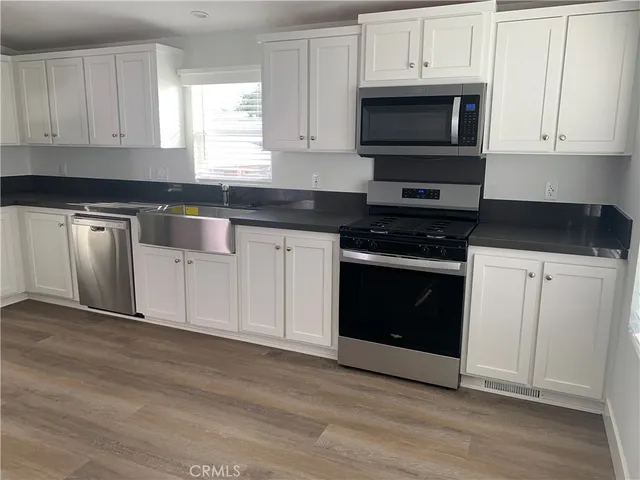a kitchen with granite countertop white cabinets and stainless steel appliances