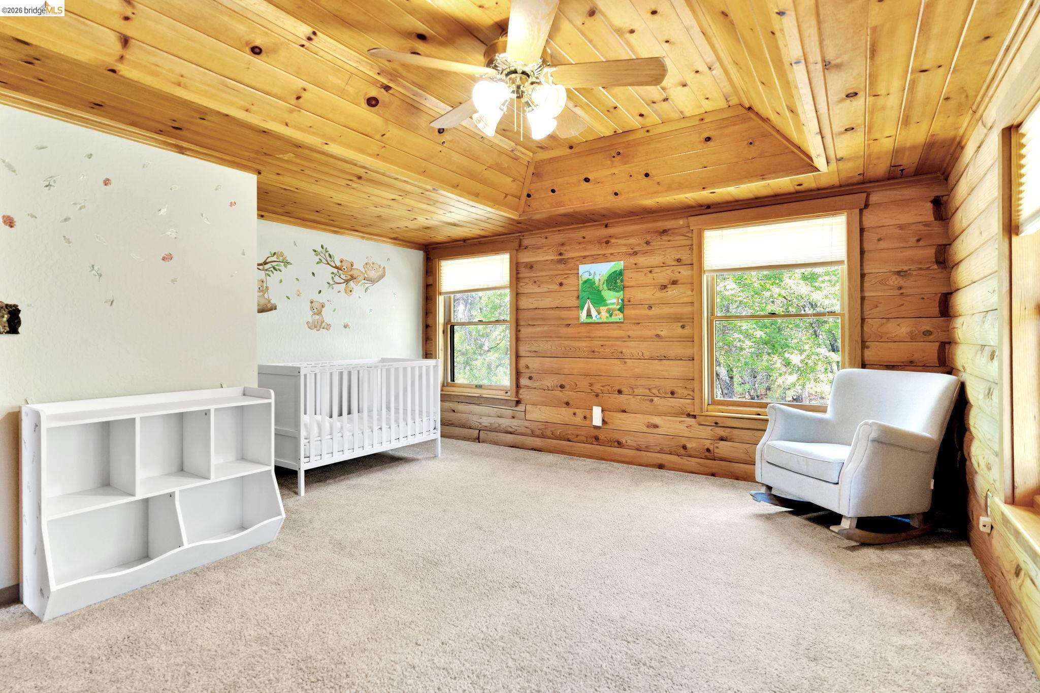 14799 Big Hill Road Sonora, CA 95370 - Photo 22 of 60 Carpeted bedroom featuring wooden ceiling, a crib, ceiling fan, and wooden walls