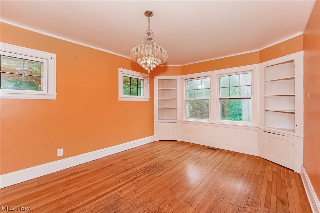 4586 Turney Road Cleveland, OH 44105 - Photo 8 of 16 Unfurnished room with a notable chandelier, built in shelves, and light hardwood / wood-style flooring