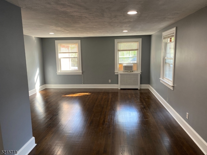 36 Elm Road Caldwell, NJ 07006 - Photo 4 of 28 an empty room with wooden floor and windows with curtains