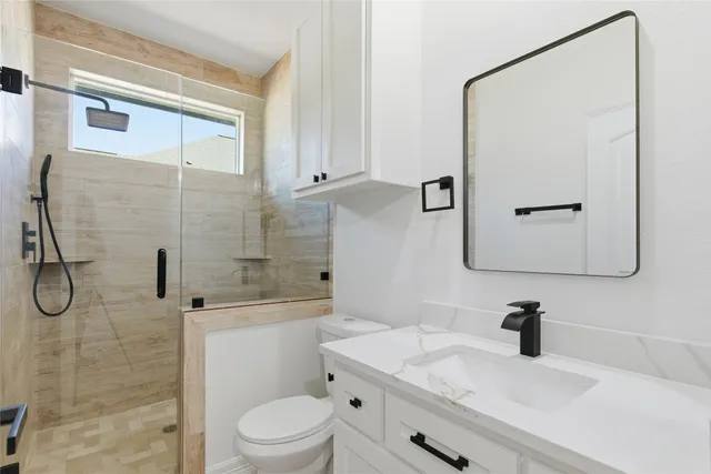 a bathroom with a granite countertop sink a toilet and shower