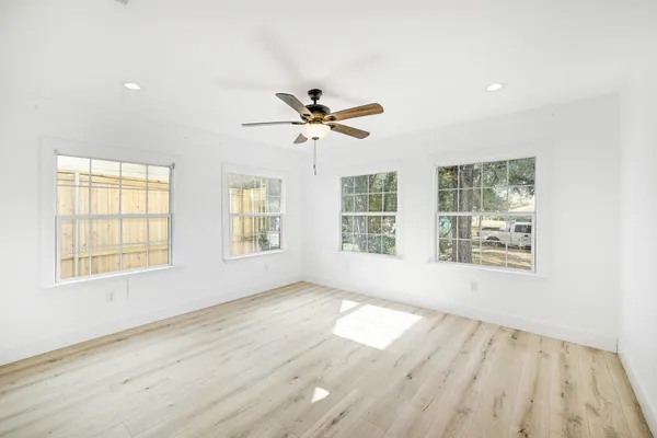 a view of an empty room with wooden floor and a window