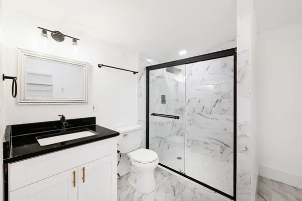 a bathroom with a granite countertop sink toilet and shower