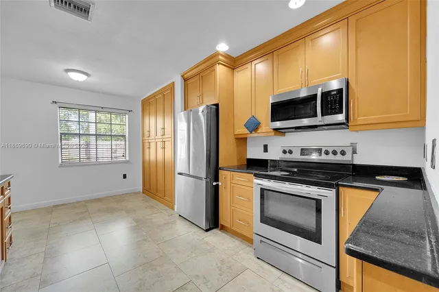 a kitchen with granite countertop a sink a stove and cabinets