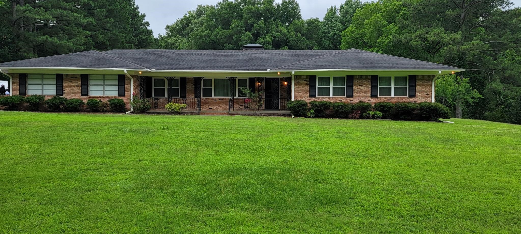 Brick exterior residence with a dark shingle roof and contrasting black shutters