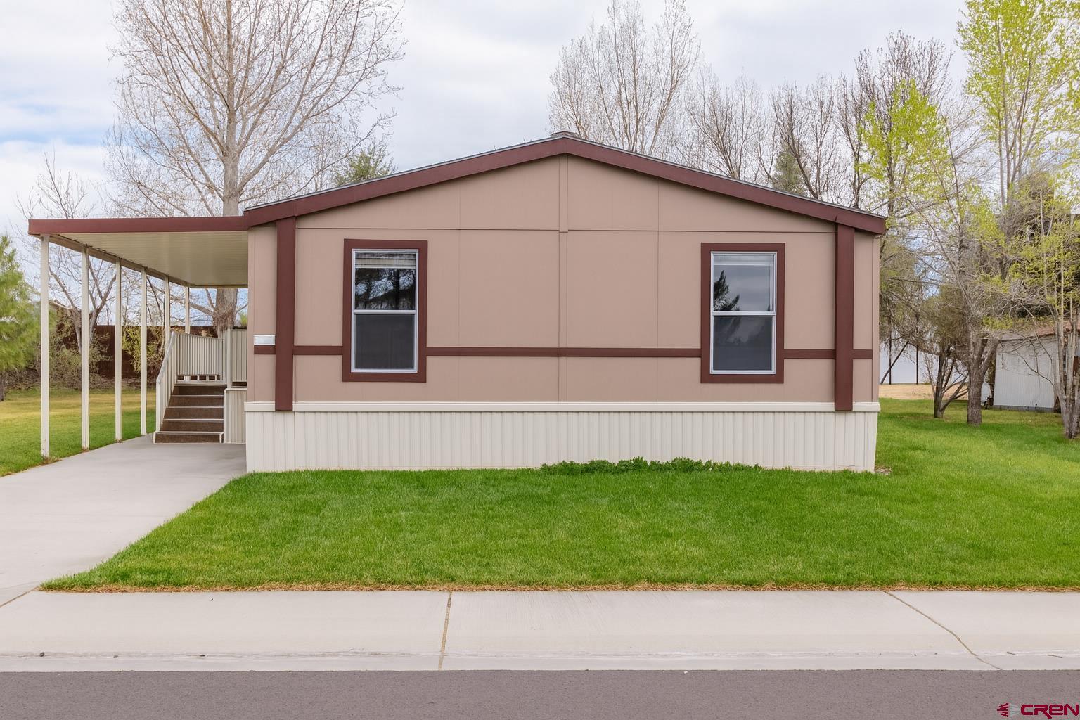 901 6530 Road, Unit 1203 Montrose, CO 81401 - Photo 2 of 22 a view of a house with a yard plants and large tree