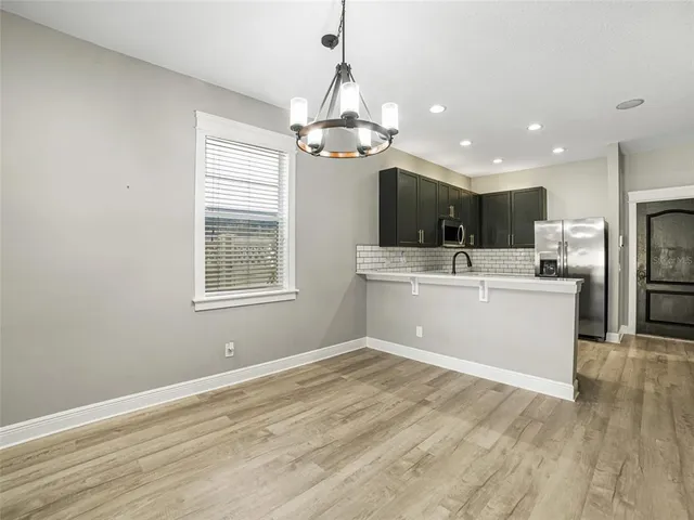 a view of a kitchen with a sink stainless steel appliances and chandelier