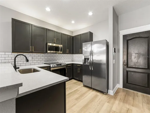 a kitchen with stainless steel appliances granite countertop a refrigerator a sink a stove and cabinets