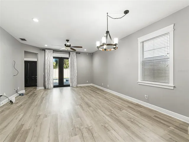 a view of an empty room with chandelier and glass door