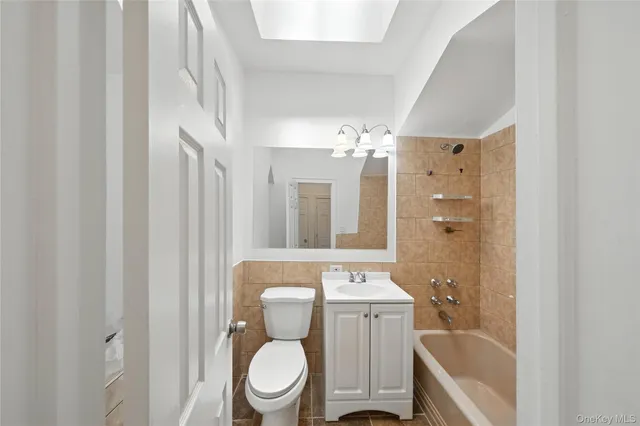 a bathroom with a toilet a sink a mirror a bathtub and vanity