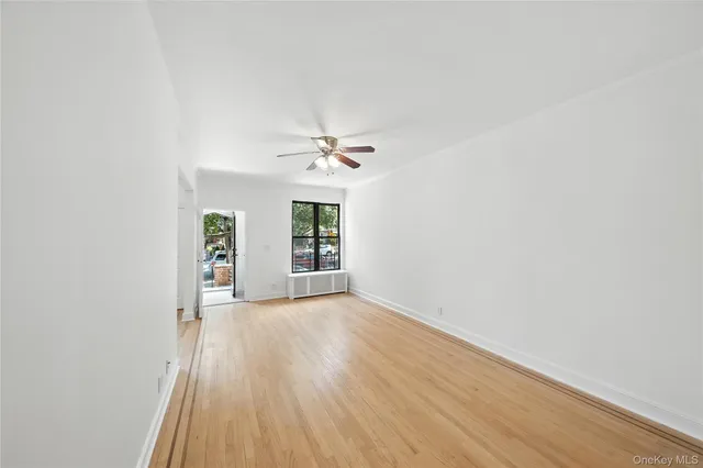 an empty room with wooden floor chandelier fan and windows