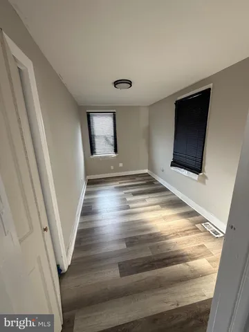 a view of an empty room with wooden floor and stairs