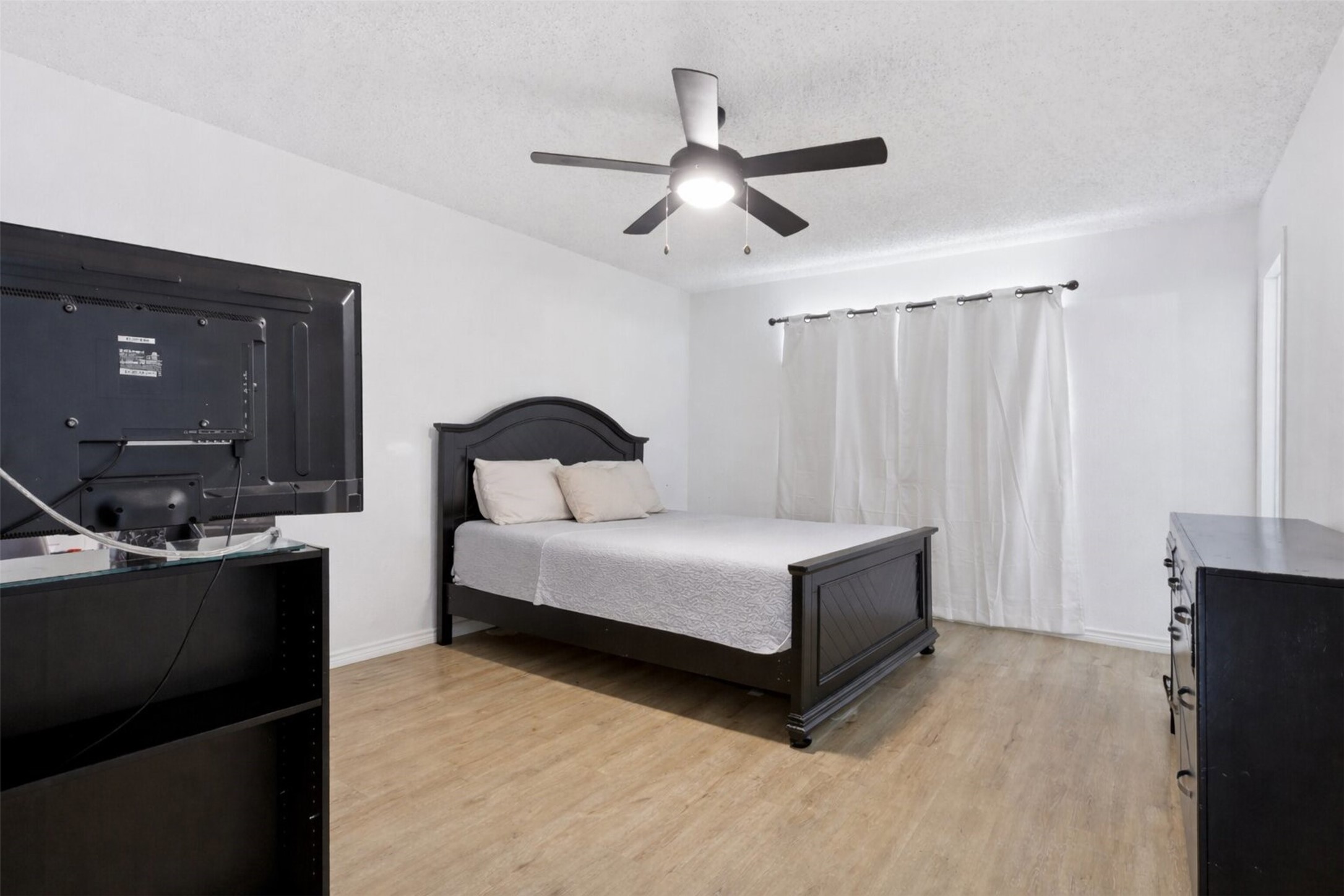 23310 Dew Wood Lane Spring, TX 77373 - Photo 13 of 24 Spacious primary bedroom, featuring modern flooring and a sleek ceiling fan