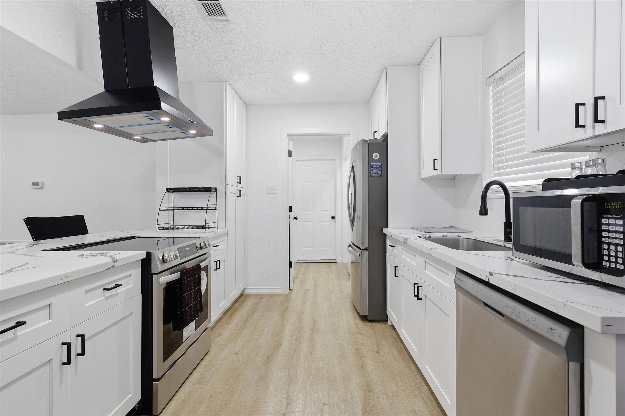 23310 Dew Wood Lane Spring, TX 77373 - Photo 2 of 24 Modern chef’s kitchen with premium quartz, black hardware, and designer vent hood