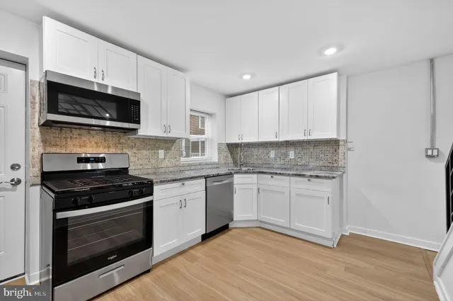 a kitchen with granite countertop white cabinets and stainless steel appliances