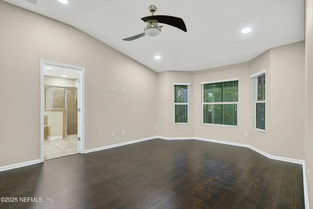 an empty room with wooden floor and ceiling fan