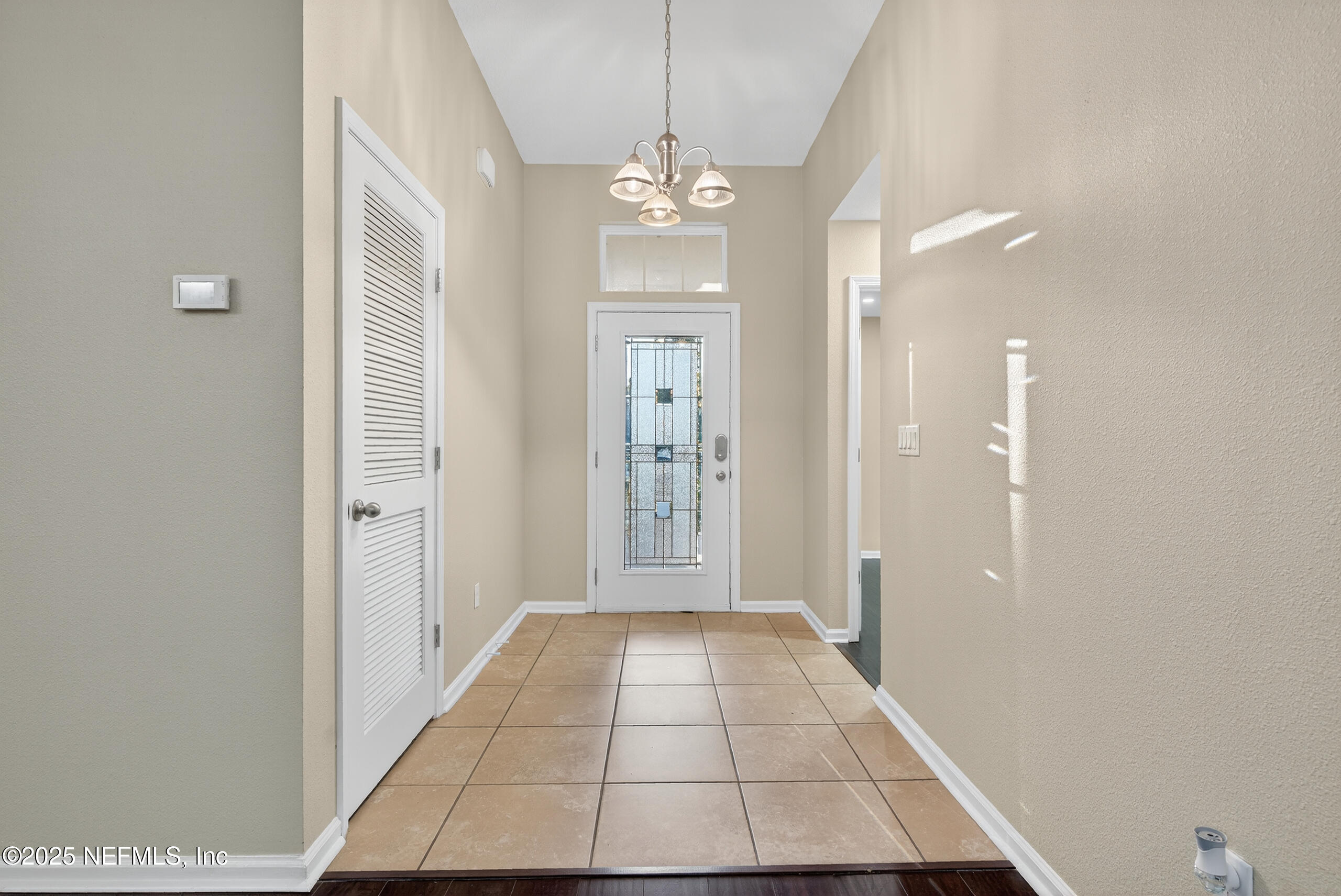 15885 Bainebridge Drive Jacksonville, FL 32218 - Photo 5 of 46 a view of a hallway with chandelier and glass door