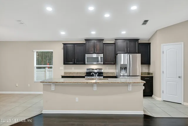 a kitchen with kitchen island stainless steel appliances cabinets a sink and a counter top