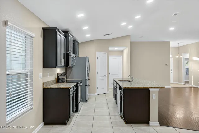 a kitchen with granite countertop a stove microwave and refrigerator