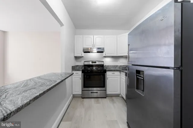 a kitchen with granite countertop white cabinets and stainless steel appliances