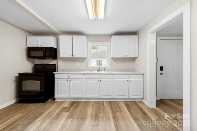a kitchen with granite countertop a stove top oven sink and cabinets